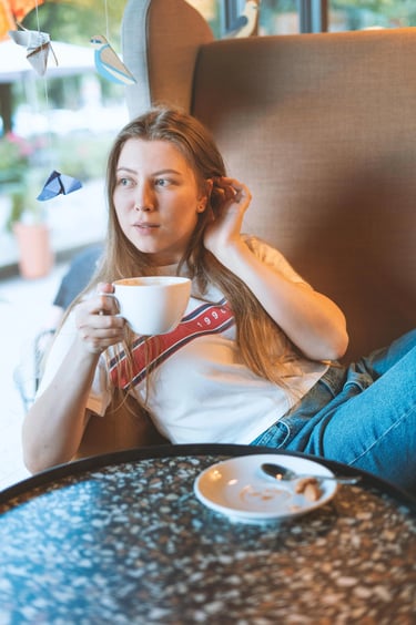 90s style portait picture of a young girl in a coffee shop drinking coffee in a big armchair  
