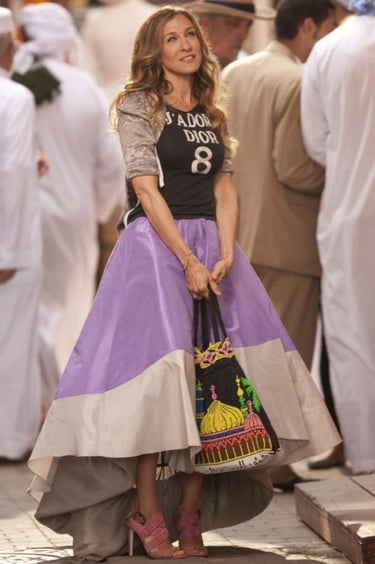 Carrie Bradshaw de la série sex and the city portant un tee shirt Dior et une jupe midi 