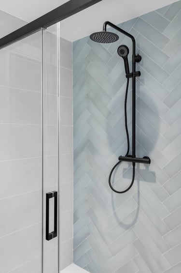 New frameless shower door with black handle and clean glass panels – demonstrates a completed shower