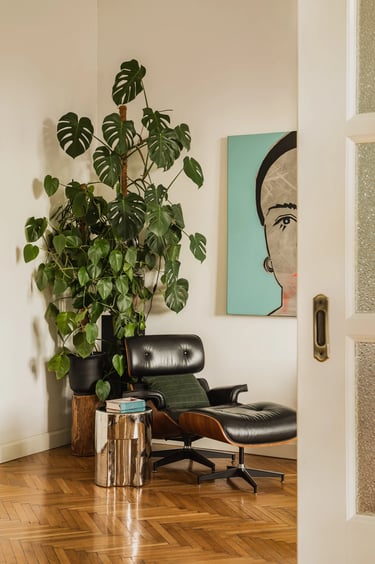 Kultowy fotel Eames Lounge Chair, duża monstera i obraz.