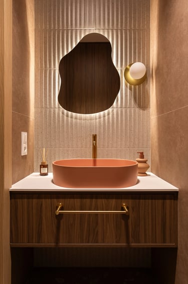 Fotografia łazienki: symetryczny kadr z różową umywalką i lustrem.