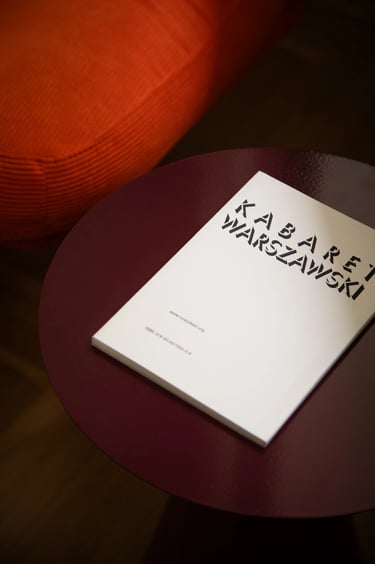 Minimalistyczny detal: kontrast bieli albumu i bordowego stolika.