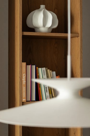 Drewniany regał z książkami i białym wazonem ceramicznym.