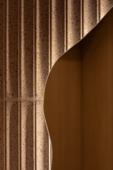 Detal faktury: ryflowane płytki, nieregularne lustro i oświetlenie.