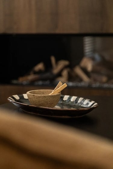 Kompozycja zdjęcia: detal stolika kawowego, ceramika i palo santo.