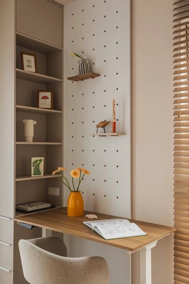 Drewniane biurko, żółty wazon i biała ścianka pegboard z półkami.