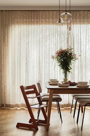 Pionowy kadr: naturalne światło w jadalni i krzesło dziecięce.