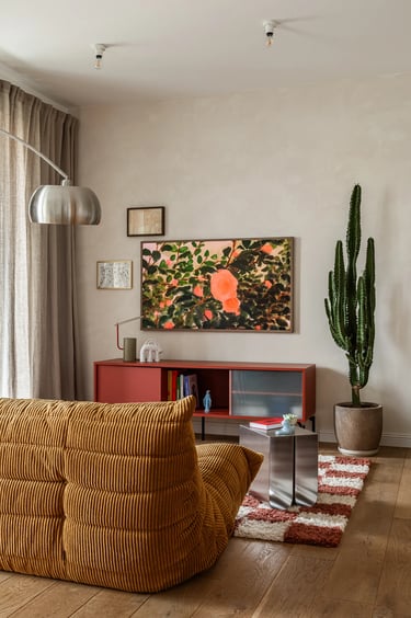 Eklektyczny salon, musztardowa sofa Togo, czerwonawa komoda RTV, duży kaktus i telewizor The Frame.