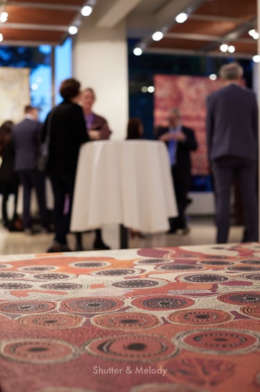 Nahaufnahme von Aborigine-Kunst mit unscharfen Veranstaltungsgästen.