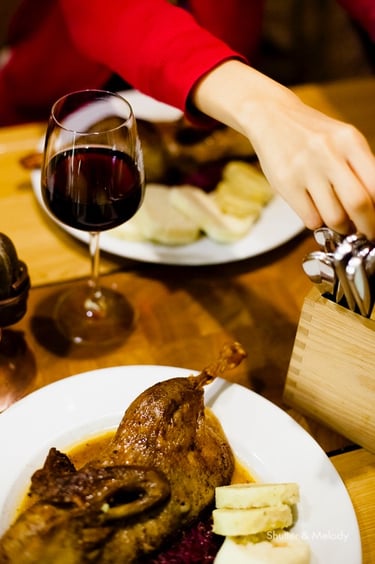 Ente mit Knödeln und einem Glas Rotwein.