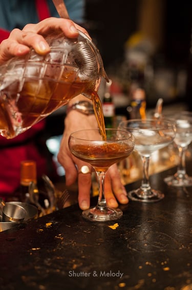 Ein Mann schenkt einen Cocktail in ein Glas ein.