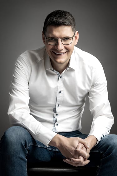 a corporate man in a white shirt and jeans sitting on a stool