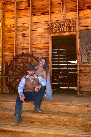 a bride and groom pose for a photo in front of a wooden building