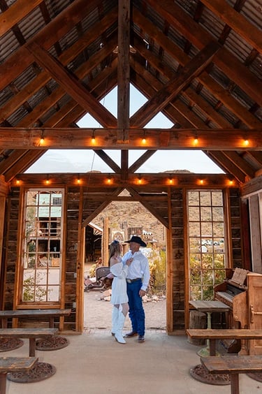 a man and woman standing in a barn like structure