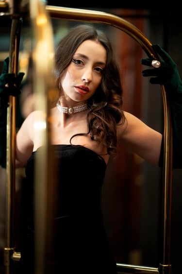 Old Hollywood style portrait photo of a woman with pearl necklace and black dress in a luggage cart