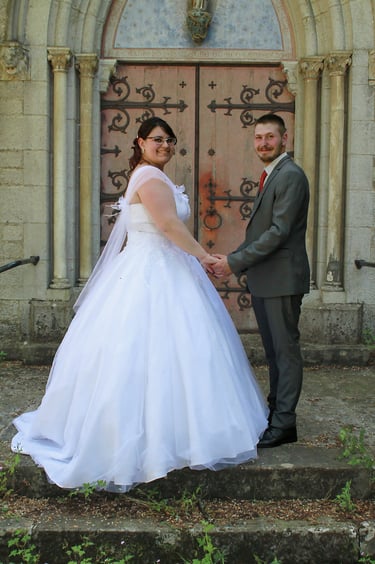 couple de mariés posant devant une porte d'église à l'occasion de la séance de photos de couple.