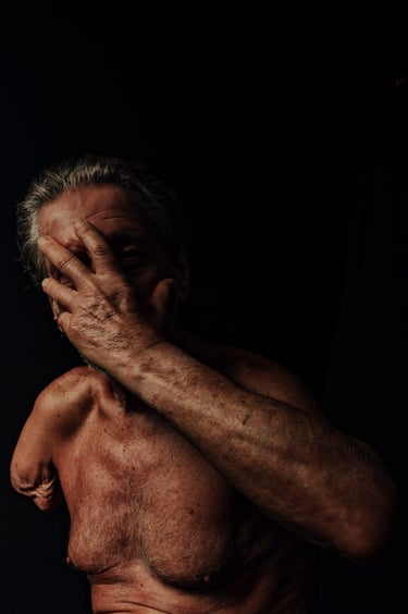 Fotografia em fundo escuro de um homem cobrindo o rosto com a mão