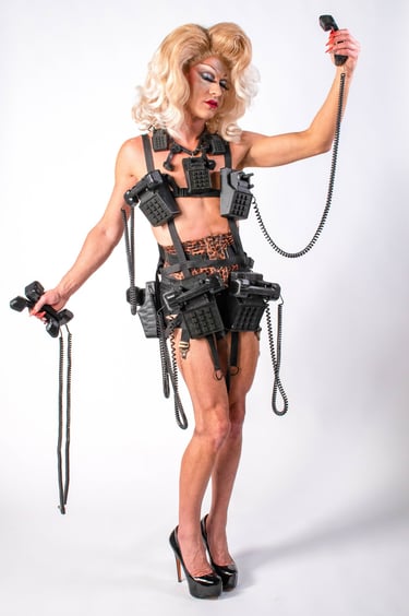 blonde drag queen in leapord print wearing a telephone themed outfit holding phone receivers/cords