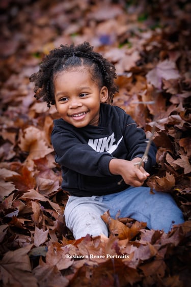 a young child sitting on a pile of leaves
