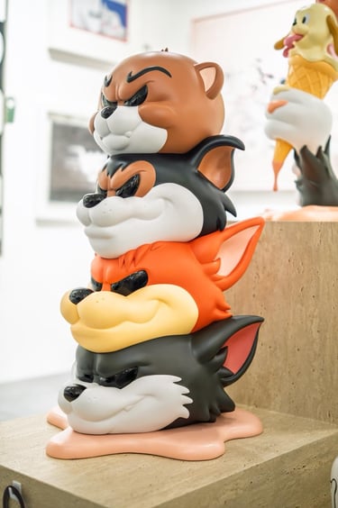 Stacked cartoon cat and bear designer toy sculpture on display in a modern art gallery.