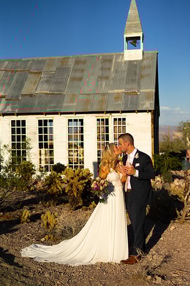 a bride and groom kissing in front of the wedding chapel