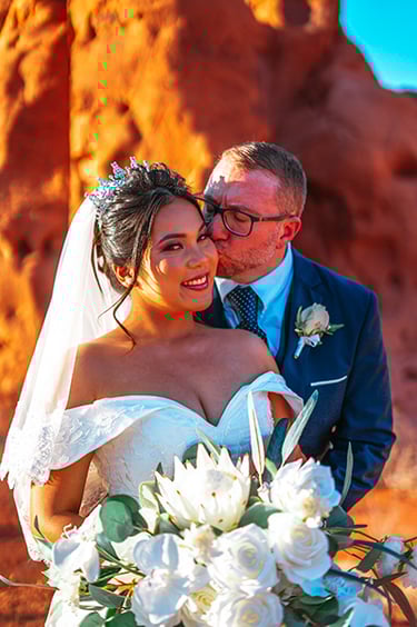 a man and woman in wedding attire standing in front of a mountain