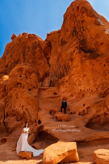 Bride and groom posing in front of towering red sandstone rock formations for a Las Vegas desert wedding.