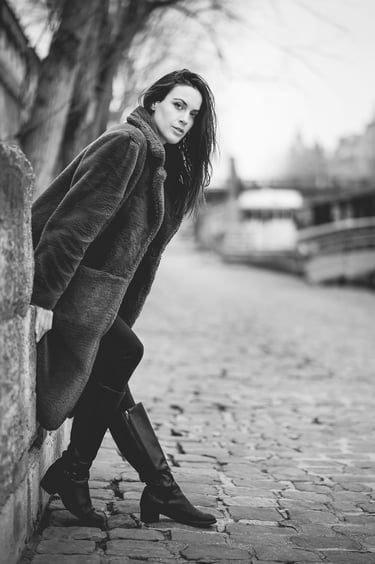 Portrait en noir et blanc d’une femme en manteau sur les quais de Seine à Paris, ambiance hivernale et lifestyle.