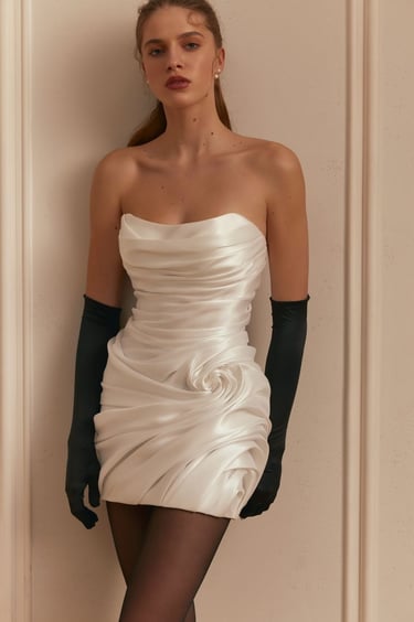 Elegant model wearing a white strapless draped satin mini dress and long black opera gloves.