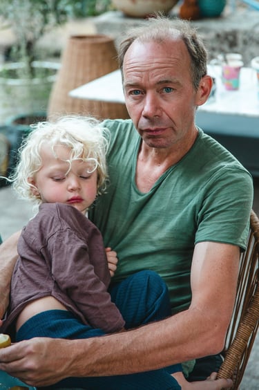 Un homme porte son fils sur ses genoux avec tendresse, par Zohra Elmes