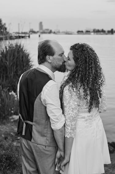 Newlywed couple kissing by a river in Amsterdam.