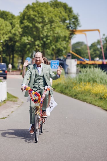 Bride and groom arriving at wedding venue on a bicycle.