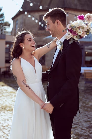 Junges Ehepaar lacht und hält Händchen.