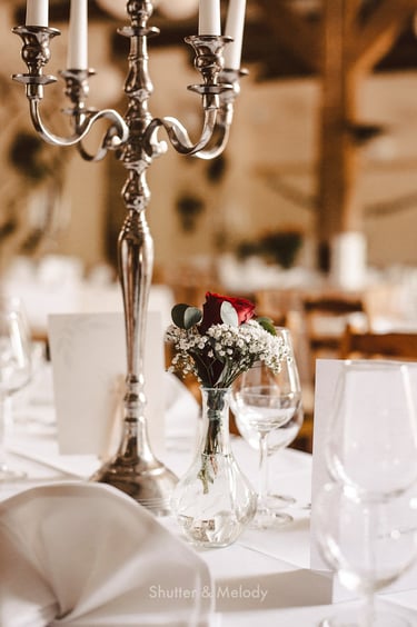 Dekorative Blumen auf einem Tisch neben einem Kandelaber.