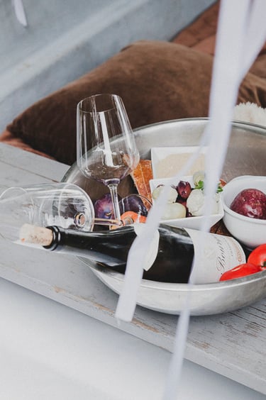 Wein, Snacks und Gläser in einer Metallschüssel.