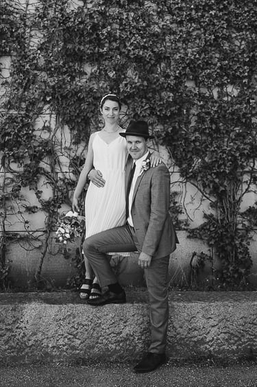 Braut und Bräutigam stehen neben einer mit Efeu bewachsenen Mauer.