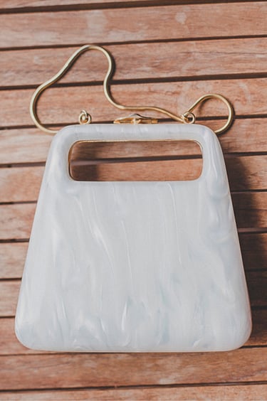 Eine Perlmutt-Handtasche auf einem Holztisch.