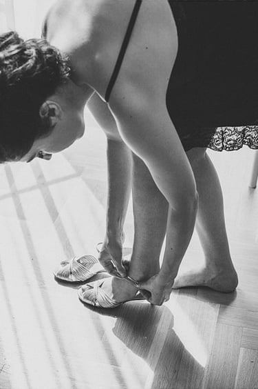 Eine Braut in einem schwarzen Unterkleid schnürt ihre Schuhe.