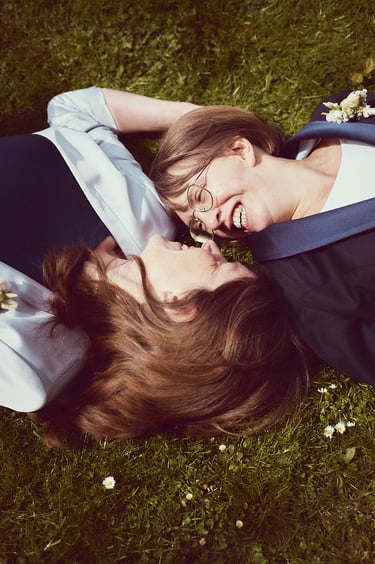 Zwei glückliche Bräute, die im Gras liegen.