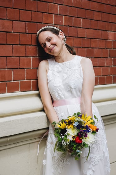 Bride holding flowers leaning against the wall.