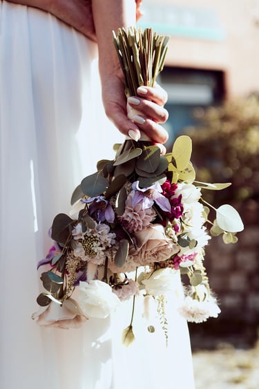 Bridal bouquet held behind her back.
