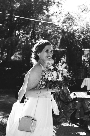 A smiling bride holding a flower bouquet.