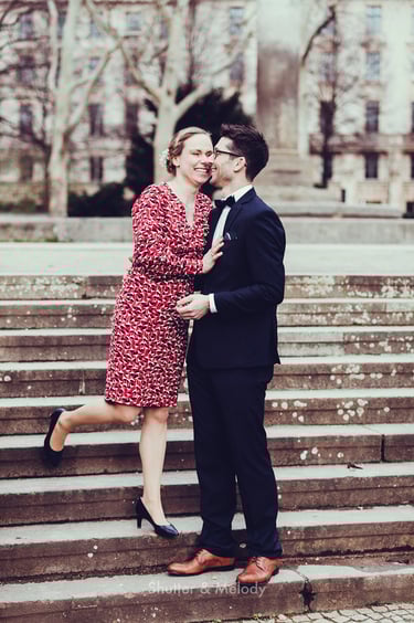 Bride and groom laughing standing on stairs.