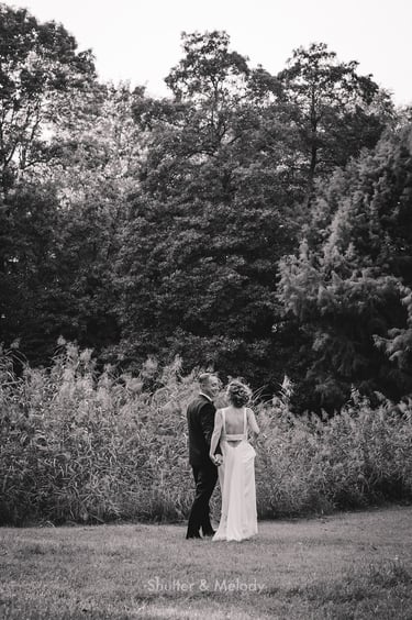 Bride and groom walking away on a meadow.