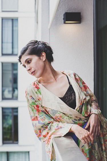 A bride in a colourful robe on a balcony.