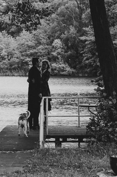 A couple standing on a pier next to a lake.