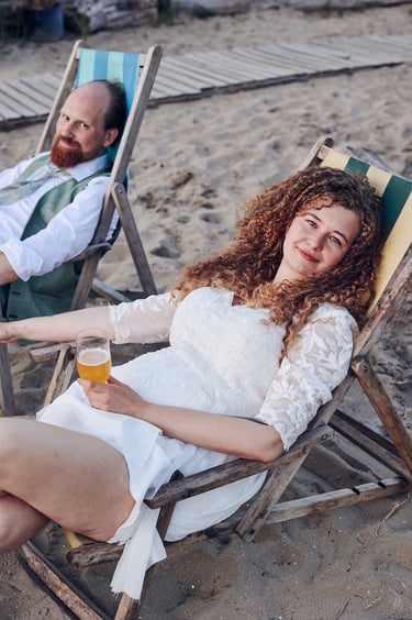 Bride sitting on a deck chair enjoying a beer.