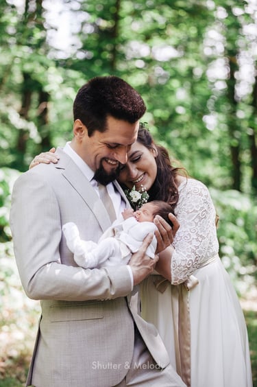 Bride and groom looking at their infant in a park.