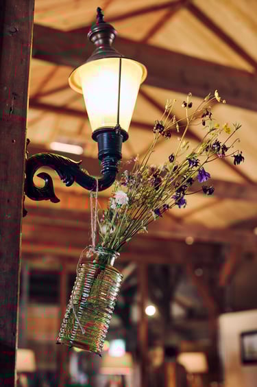 Vase with flowers handing from a wall lamp.