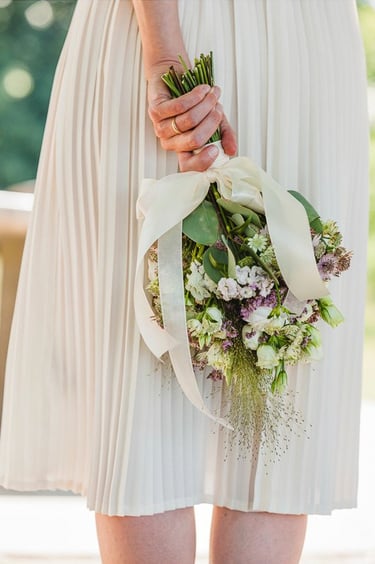 Bride holding flowers behind her back.